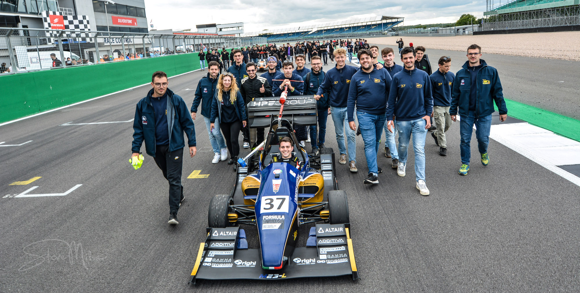 Formula Student UK 2023 overall winners - Modena_2 MoRe Modena Racing team members walking behind their car on the pit straight of Silverstone circuit